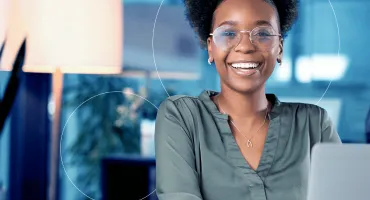 Mulher sorrindo, sentada na mesa de seu escritório