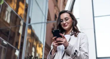 Mulher sorrindo enquanto tecla no celular